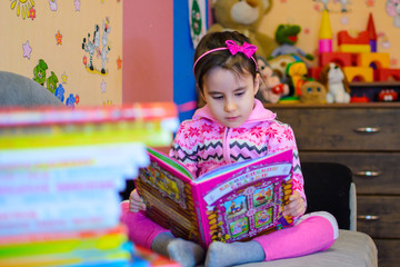 Cute girl on the background of her toys with a book