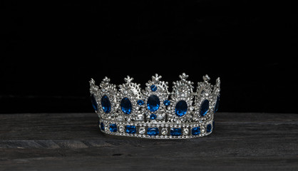 silver royal crown on a black wooden background © serikbaib