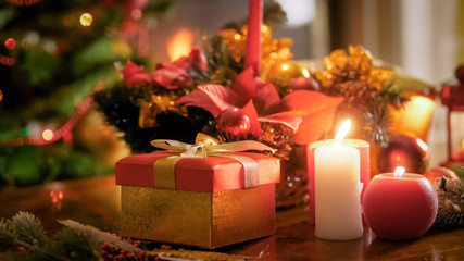 Fototapeta na wymiar Closeup image of Santas' present in red box on wooden table against Christmas tree