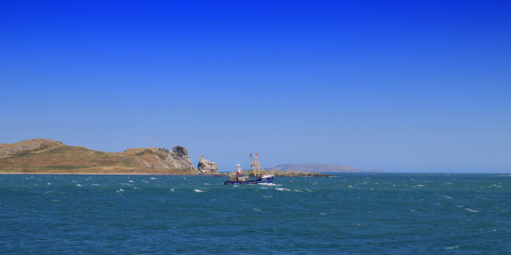 A fishing trawler passing the uninhabited island of Irelands Eye off  Howth Harbour in Dublin, Ireland.  