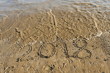 Year 2018 written in the sand of the beach