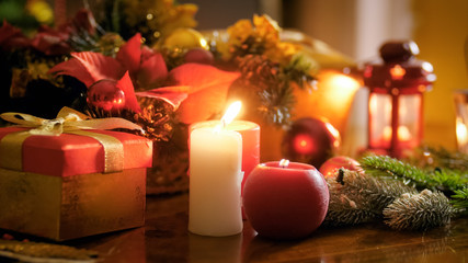 Closeup image of gift box and burning candles on Christmas eve