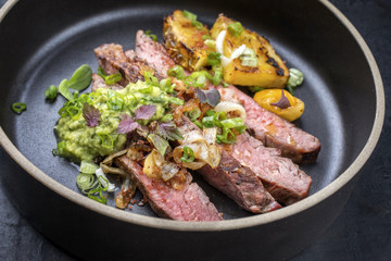 Modern Barbecue dry aged wagyu flank steak with pineapples and chimichurri sauce as closeup on a plate .