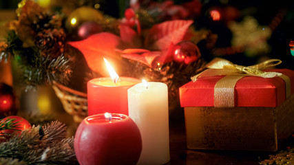 Closeup photo of three burning candles and golden gift box with ribbon bow. Perfect backgorund for winter holidays and celebrations