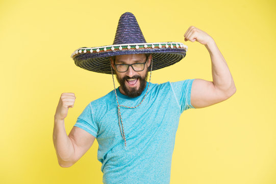 Man cheerful face in sombrero hat posing with biceps muscles strong gesture yellow background. Mexican party concept. Guy looks festive in sombrero. Party and holiday. Mexican traditional attribute