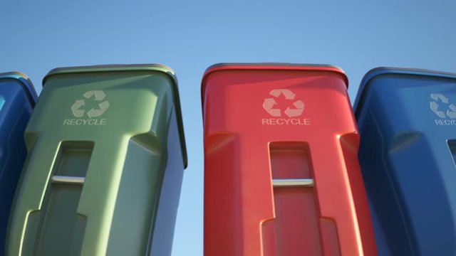 Colorful plastic garbage bins stacked in a row against a clear sky background.