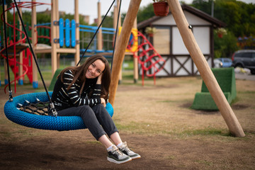 authentic portrait of a young smiling woman on a hanging swing, the concept of freedom, day off,...