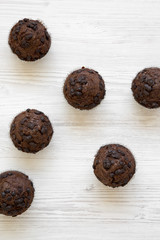 Freshly baked chocolate cupcakes on white wooden table, top view. Overhead, from above.