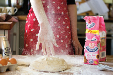 Hand throwing flour onto dough