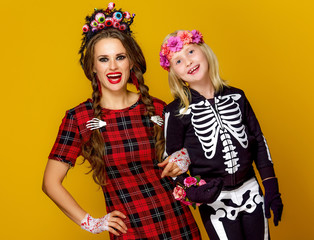 mother and daughter in halloween costume isolated on yellow