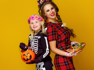 smiling modern mother and daughter with Halloween candies