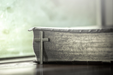 Cross with holy Bible on wooden table