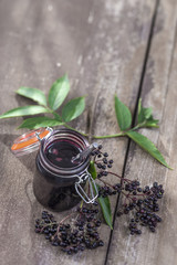 Elderberry Jam. Jar of homemade elderberry confiture and fresh fruits on old wooden background
