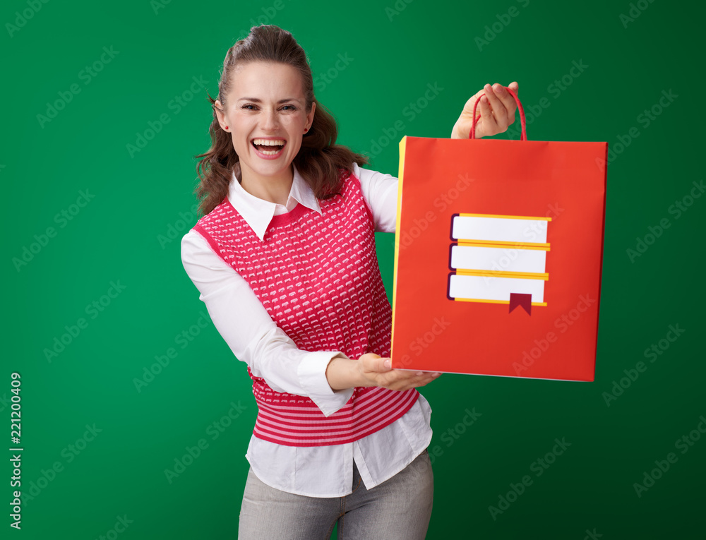 Wall mural smiling young student woman showing shopping bag with books