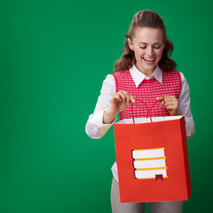 smiling young student woman looking at shopping bag with books