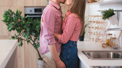 A young couple in love kiss and hug in kitchen