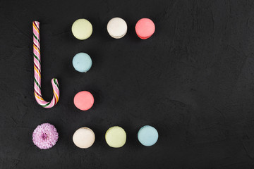 Obraz na płótnie Canvas Colorful macaroons, lollipop and flowers on stone table. Sweet macarons. Top view with copy space for your text
