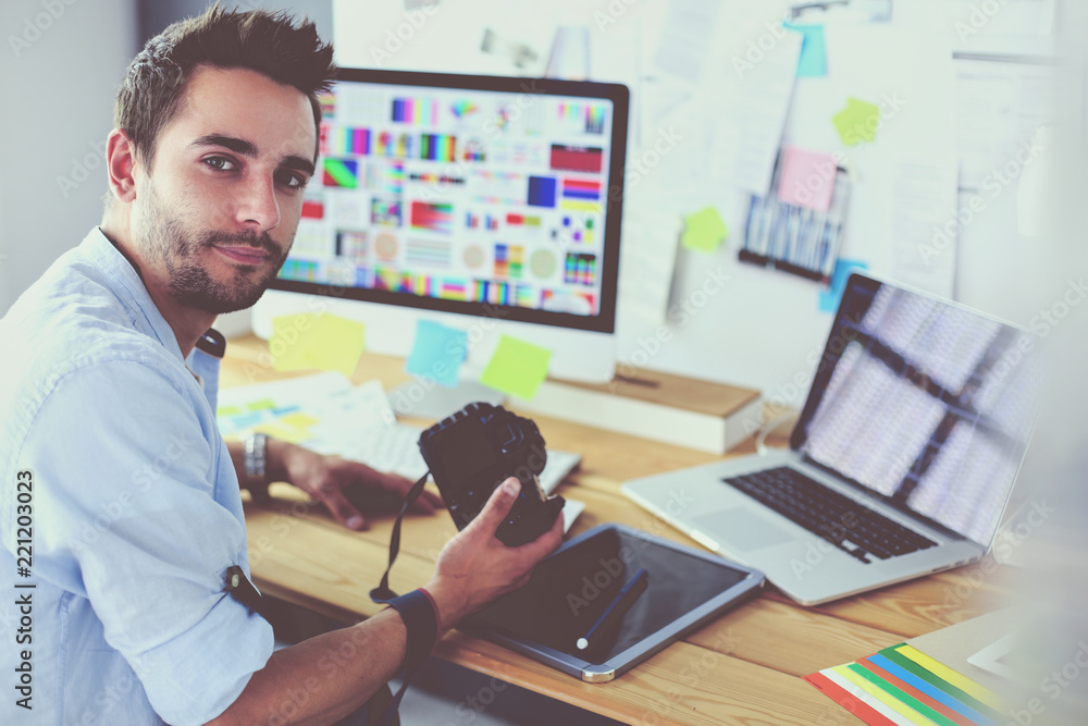Poster portrait of young designer sitting at graphic studio in front of laptop and computer while working o