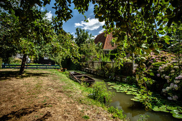 Fototapeta na wymiar Water canal in old Dutch town with wooden vintage rowing boat, fruit orchard and traditional wooden houses