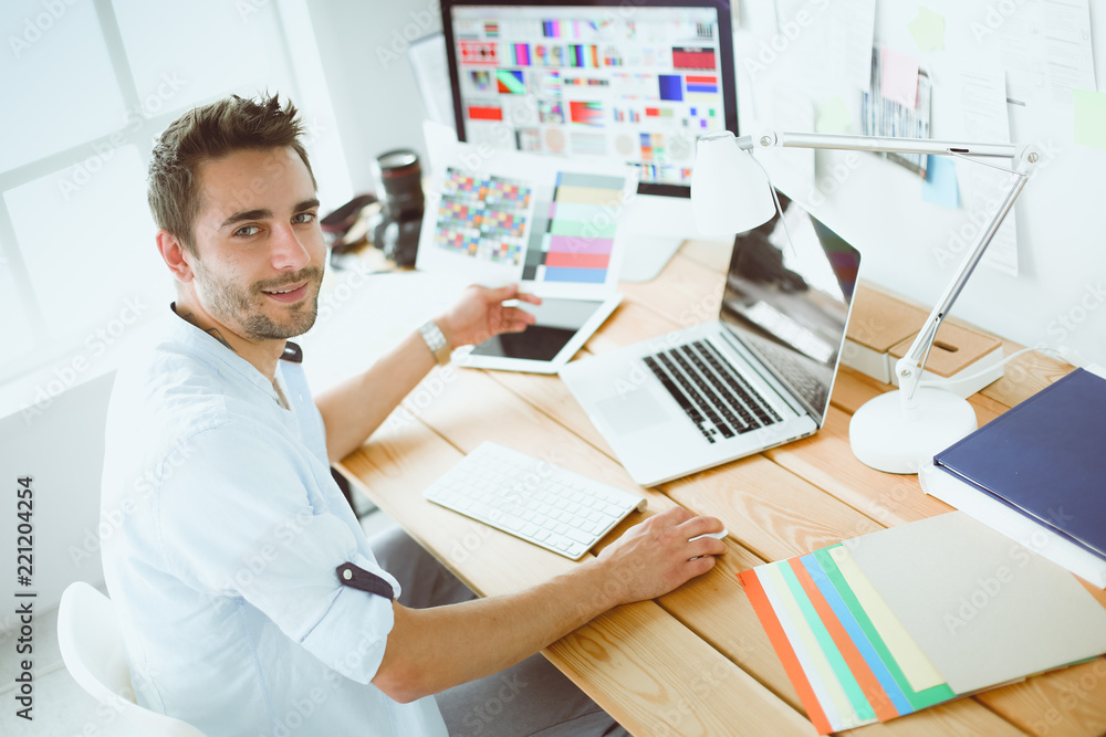 Aufkleber portrait of young designer sitting at graphic studio in front of laptop and computer while working o