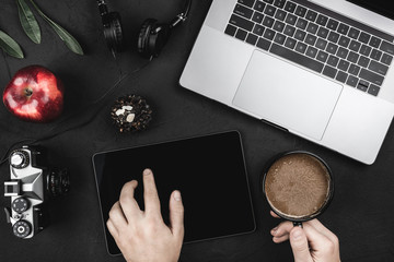 Man using app with digital tablet, sitting at cafe. Top view of laptop and headphones, red apple on a black table, flat lay