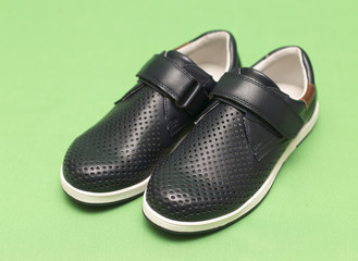 children's black shoes on a green background