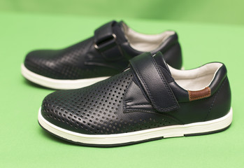 children's black shoes on a green background