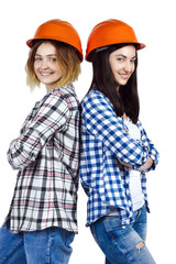 Two happy funny cute architects female woman girl in orange construction protection building helmets on isolated background. Design architecture studio concept