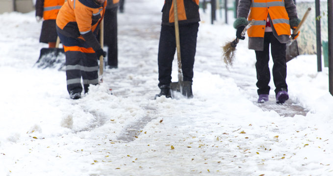 Employees of municipal services in a special form clear the snow from the sidewalk