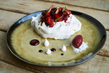 Summer fruit cake dessert Paclova. Served meringues pavlova cake with fresh berries and custard cream, close-up