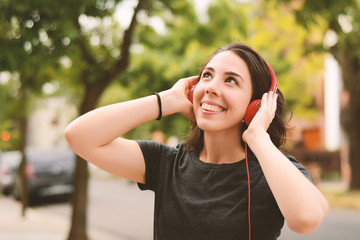 Portrait of young beautiful woman with red headphones listening music