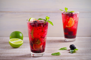 Blackberry mojito cocktail with berries, lime and mint on wooden background. horizontal
