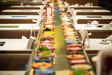 Row of dishes in belt japanese food buffet. trendy popular restaurants. healthy food type of boiled instead fried trans-fat. image for background, objects and copy space.