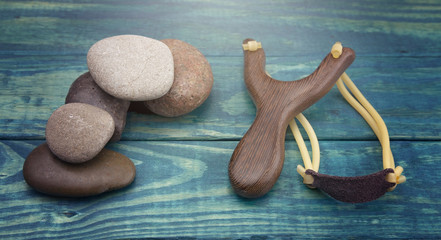 Slingshot and Five Smooth Stones on a Blue Table