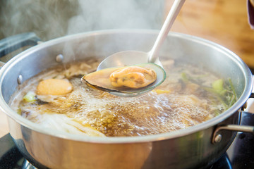Shabu Shabu and Sukiyaki black soup, show squid slice on ladle. healthy food japanese style. image for objects and copy space.