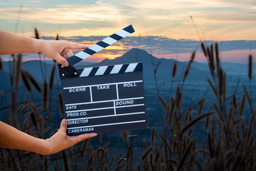 Man hands holding movie clapper isolated on nature background. Shown slate board. use the colors...