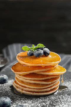 Tasty pancakes with berries and honey on slate plate