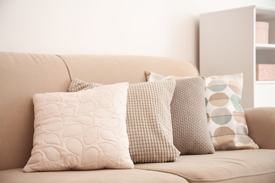 Different soft pillows on sofa in room