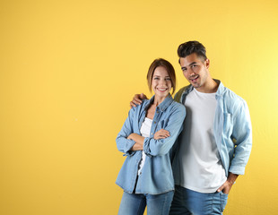 Young couple in stylish clothes on color background. T-shirts as mockup for design
