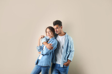 Young couple in stylish jeans on color background