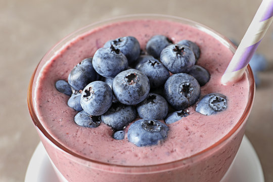 Glass with blueberry smoothie on grey background, closeup