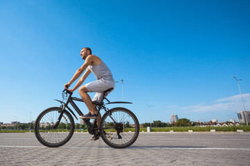 beautiful young guy with a bicycle against the sky on a sunny day