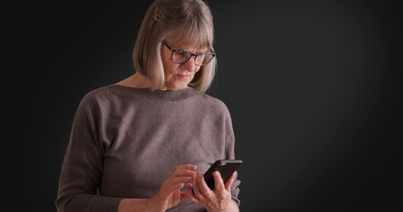 Somber lady reading worrying message on mobile device on dark gray background