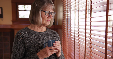 Serious mature woman holding coffee cup in domestic living room setting