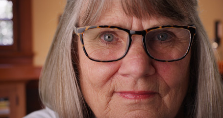 Close-up of old white woman with prescription glasses staring at camera indoors