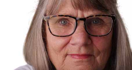 Tight shot of somber elderly woman wearing eye glasses on white background
