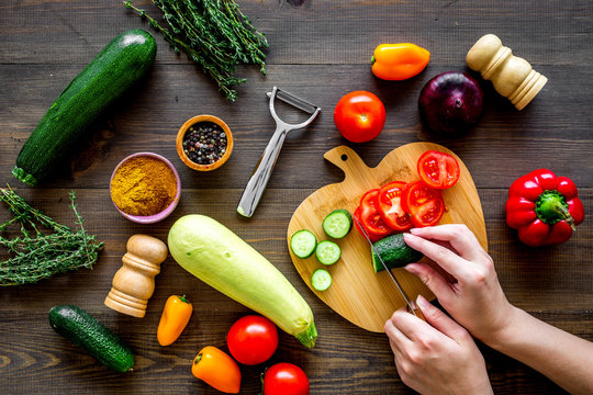 Cut different fresh vegetables on cutting board for cooking vegetable stew. Dark wooden background top view