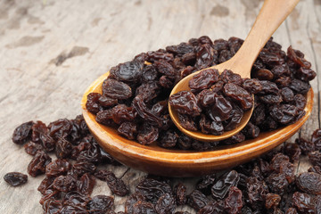 Organic dried raisins in wood spoon on wooden table, Currant