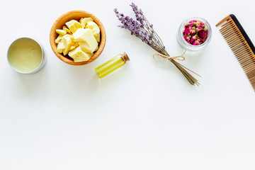 Hair treatment with natural products. Jojoba, argan, coconut oil near bunch of lavender and hairbrush on white background top view copy space