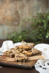 Homemade Chewy Granola Bars Wrapped in Parchment Paper and String on a Wood Cutting Board on Wood Table